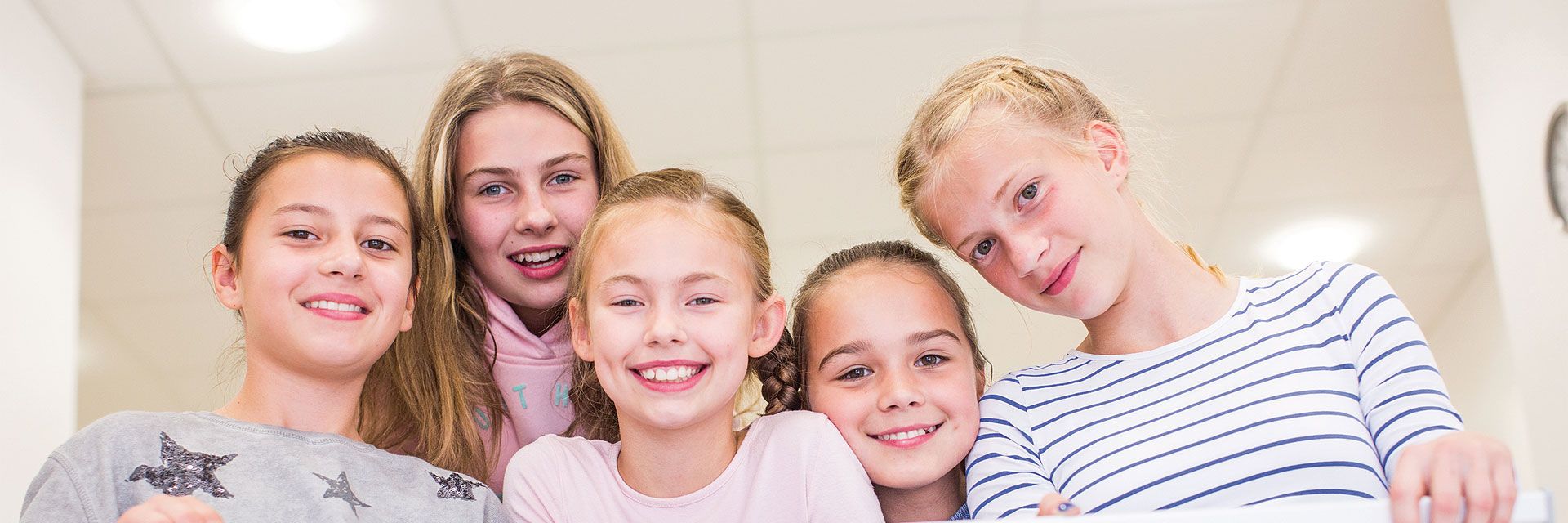 Foto: Mehrere Kinder halten ein DRK-Banner und blicken lachend in die Kamera.